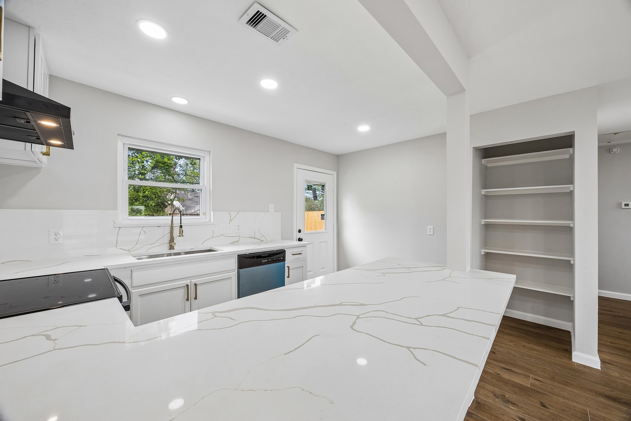4203 Mowery Road Houston, TX 77047 - Photo 11 of 16 a large white kitchen with kitchen island a sink a stove a dining table and chairs with wooden floor