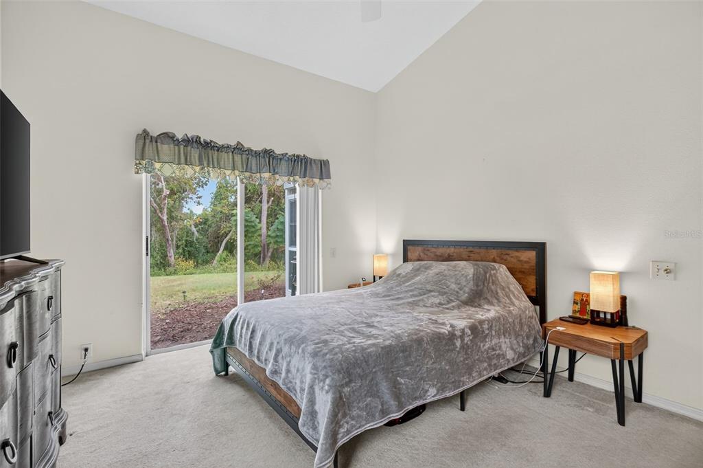 8841 Kipling Avenue Hudson, FL 34667 - Photo 17 of 41 a bedroom with a bed lamp and a large window