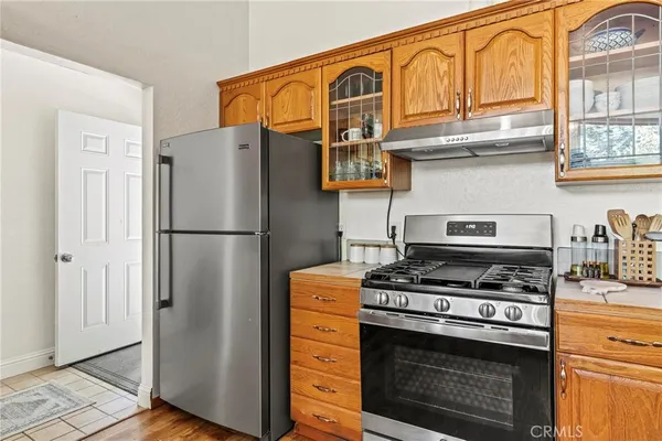 a kitchen with stainless steel appliances granite countertop a stove top oven a refrigerator a sink and dishwasher with wooden floor