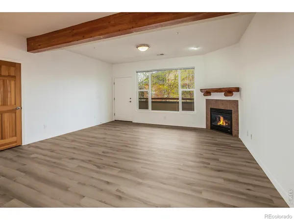 a view of empty room with wooden floor and fireplace