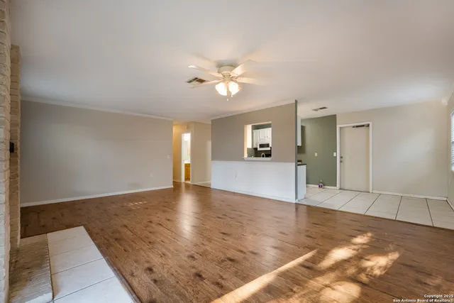 a view of an empty room with window and wooden floor