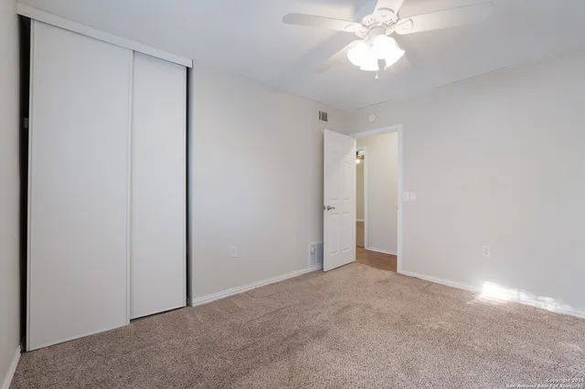 a view of an empty room and chandelier fan