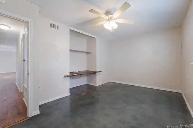 an empty room with a ceiling fan and a window