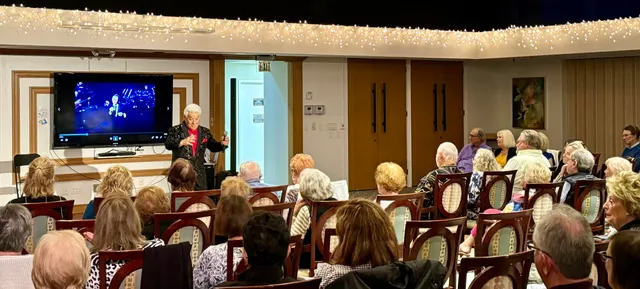 a view of a swimming pool with a lawn chairs and palm trees