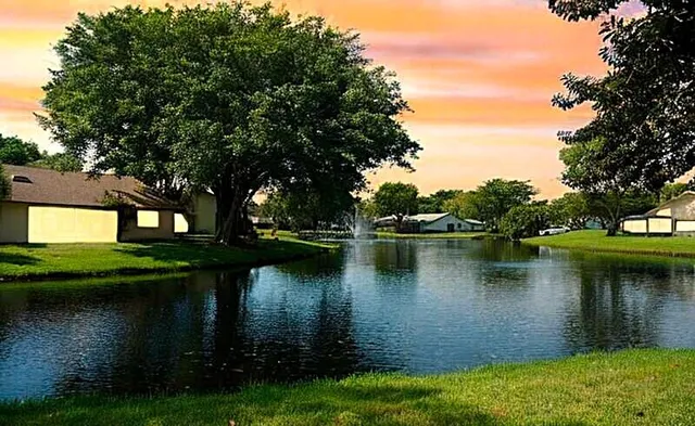 a view of a lake with a yard and large trees