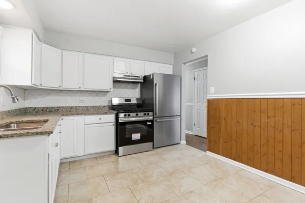a kitchen with granite countertop a refrigerator stove and sink