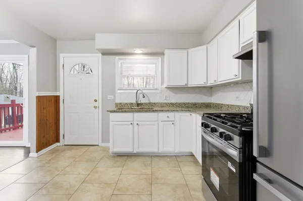 a kitchen with granite countertop a stove a sink and a refrigerator