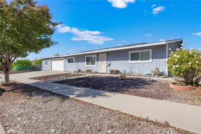 a front view of house with yard and trees in the background