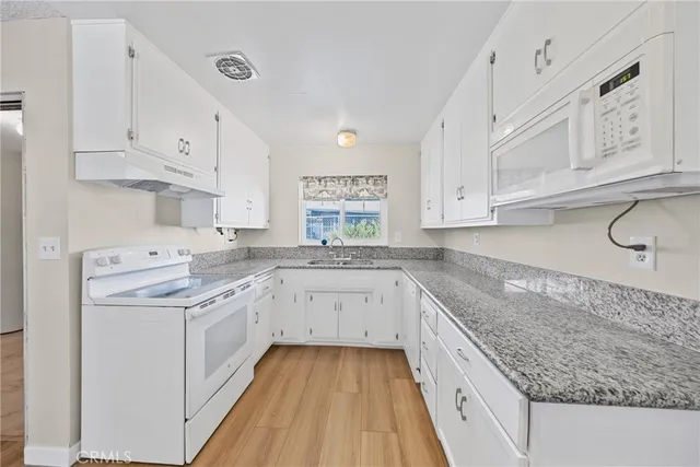 a kitchen with granite countertop cabinets stainless steel appliances and a sink