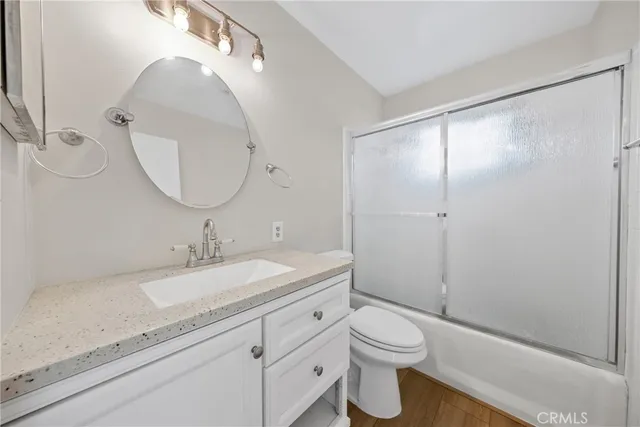 a bathroom with a granite countertop sink toilet mirror vanity and shower