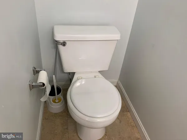 a white toilet sitting next to a white wooden wall