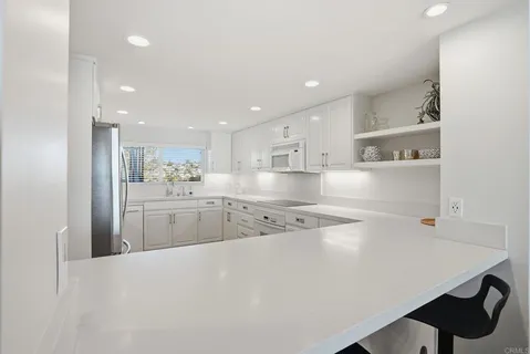 a kitchen with stainless steel appliances a refrigerator sink white cabinets and wooden floor