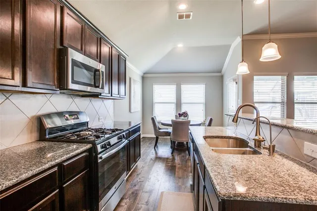 a kitchen with stainless steel appliances granite countertop a stove a sink and a microwave