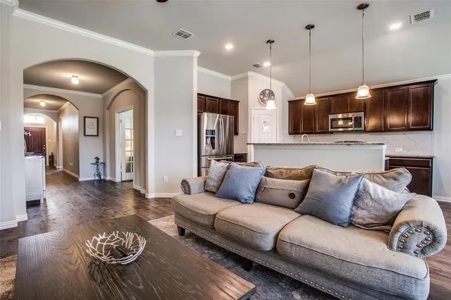 a living room with furniture kitchen view and a wooden floor