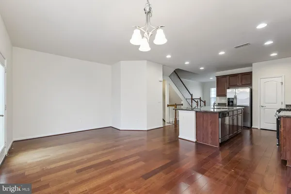 a kitchen with granite countertop wooden floors a stove a sink and a white refrigerator