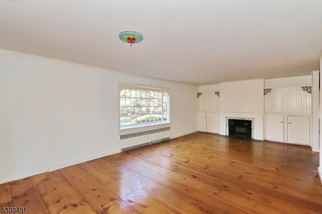 a view of empty room with wooden floor and fireplace