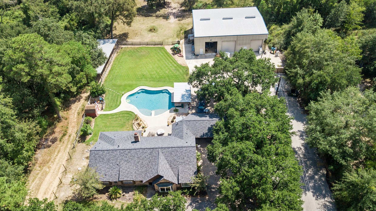 an aerial view of a house with a swimming pool a yard and a fountain