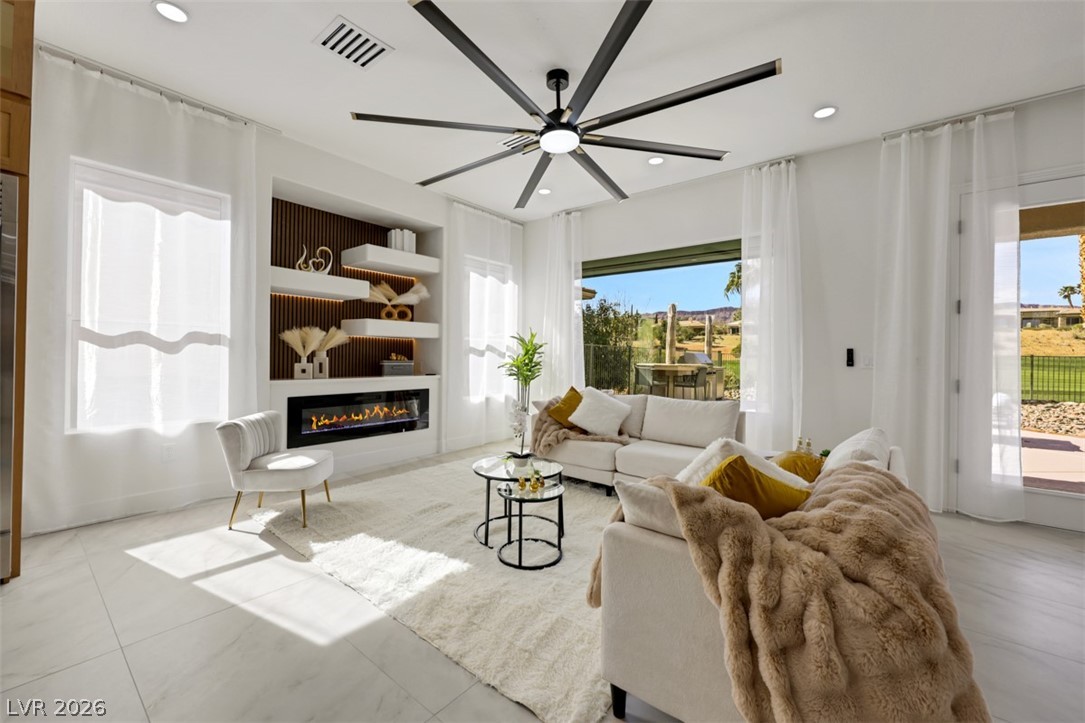 5015 Rivedro Street Las Vegas, NV 89135 - Photo 26 of 91 A well-lit living space features a modern fireplace and serene golf course views through large windows.