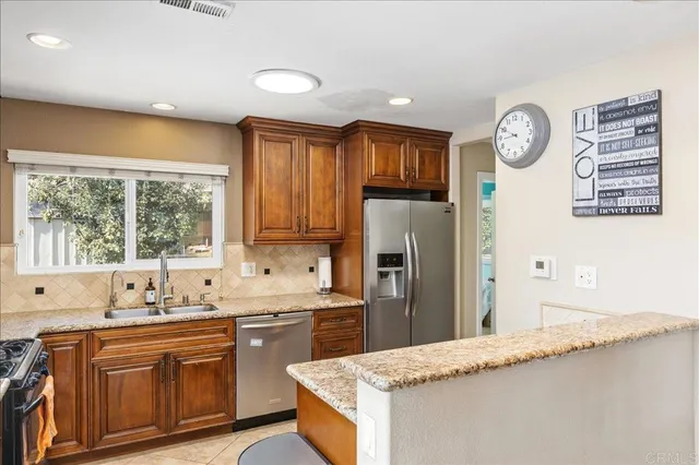 a kitchen with stainless steel appliances granite countertop a sink a stove and a refrigerator with wooden floor