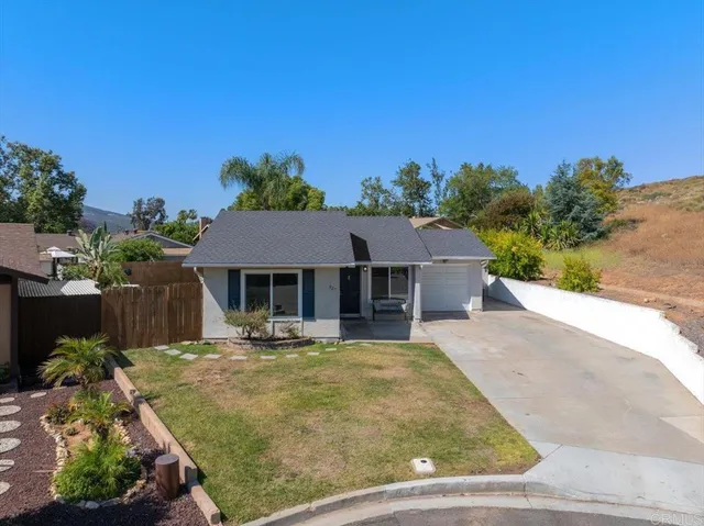 a view of a house with a small yard plants and a large tree