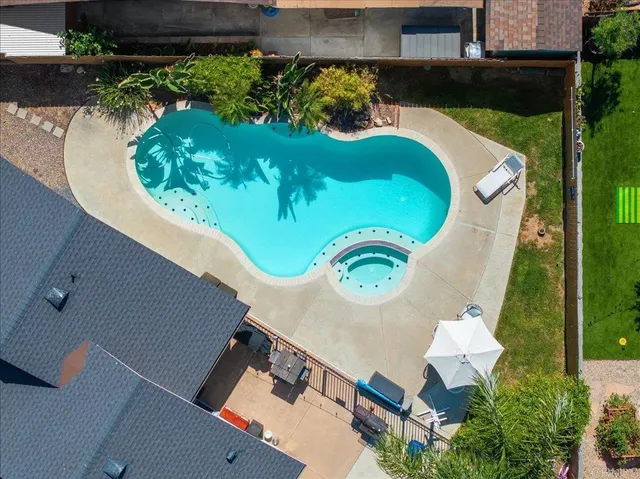 an aerial view of a swimming pool with outdoor seating and yard