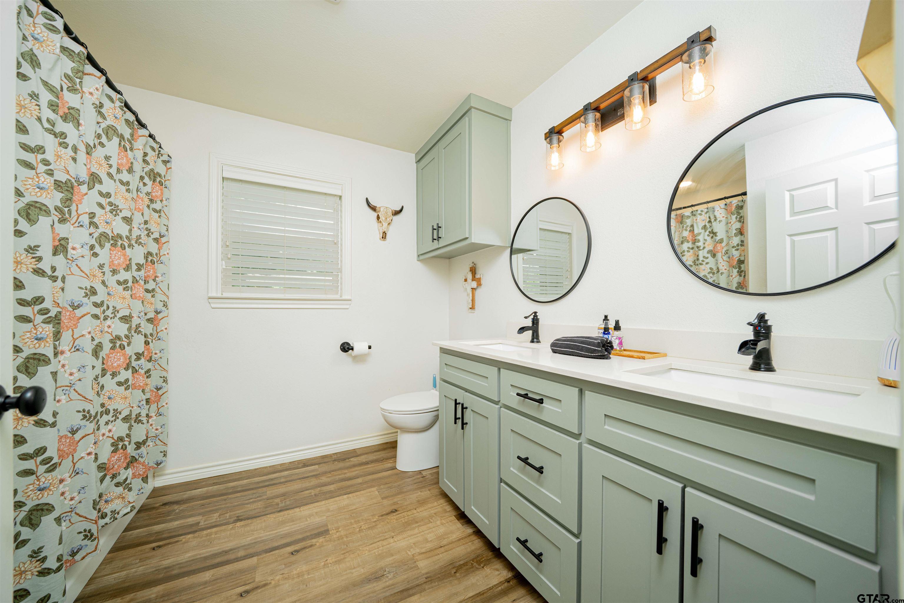 400 Crestview Hughes Springs, TX 75656 - Photo 23 of 32 a bathroom with a toilet a sink and a mirror