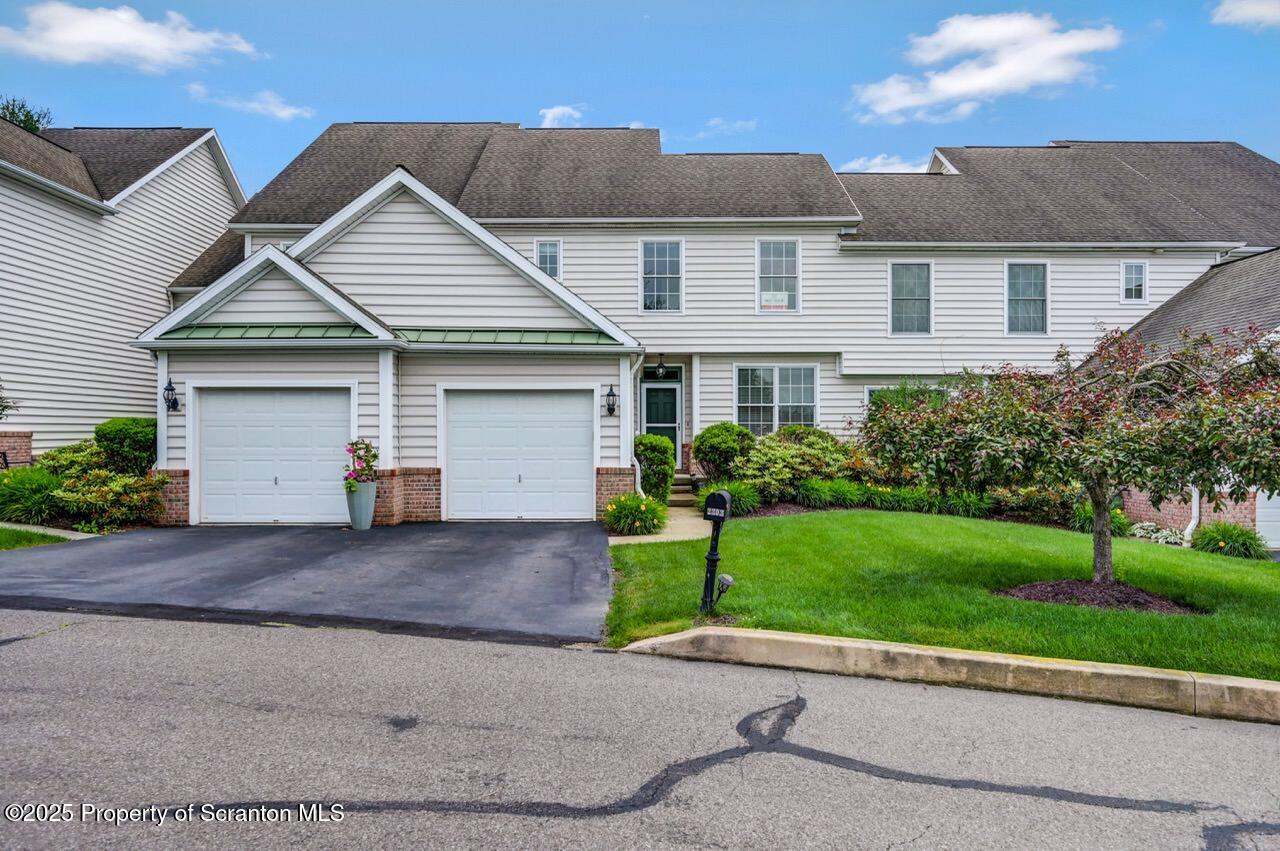 a view of a house with a yard and a large tree center in front of it