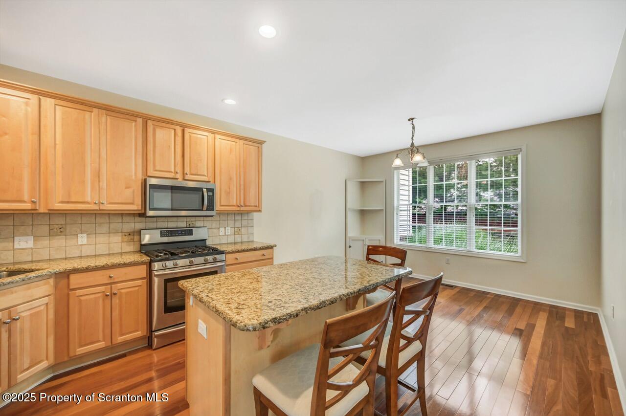 2303 Browning Cl Moosic, PA 18507 - Photo 15 of 71 a kitchen with stainless steel appliances granite countertop a stove top oven a sink a dining table and chairs with wooden floor