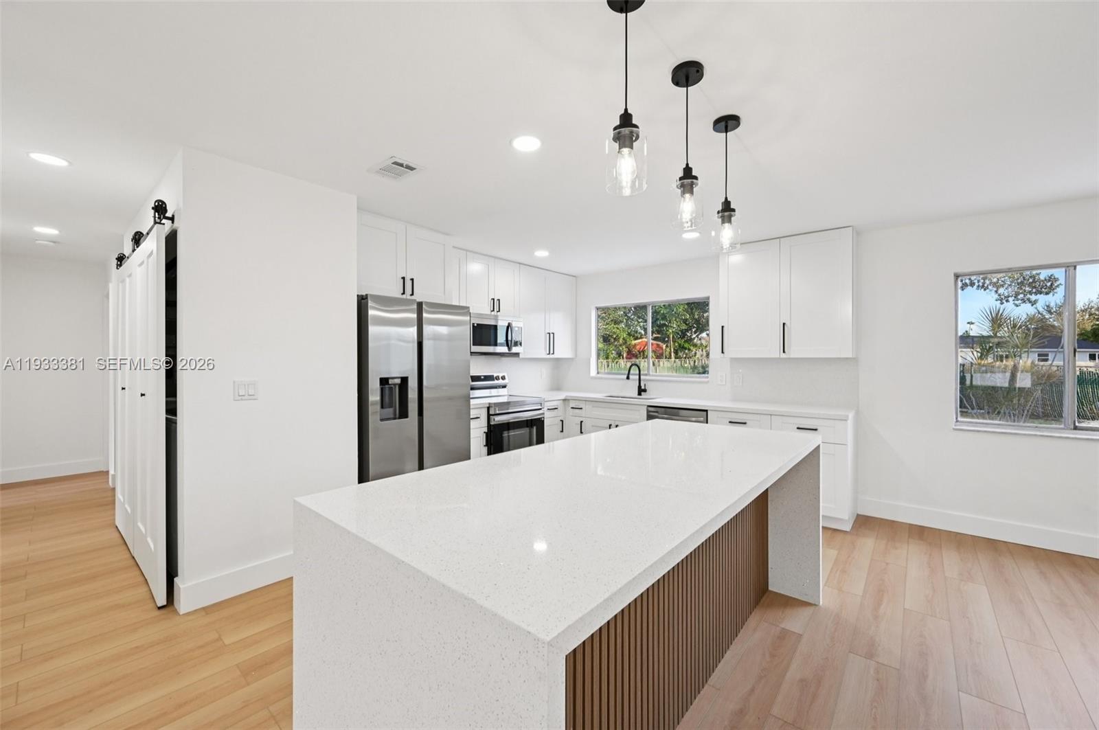 337 Southwest Cherryhill Road Port St. Lucie, FL 34953 - Photo 12 of 30 a large kitchen with kitchen island a stove a refrigerator a sink a center island and wooden floor