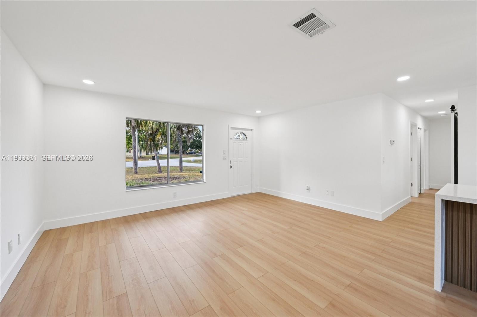 337 Southwest Cherryhill Road Port St. Lucie, FL 34953 - Photo 7 of 30 an empty room with wooden floor and windows