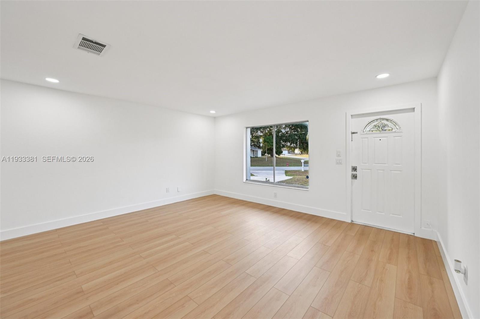 337 Southwest Cherryhill Road Port St. Lucie, FL 34953 - Photo 8 of 30 an empty room with wooden floor and windows