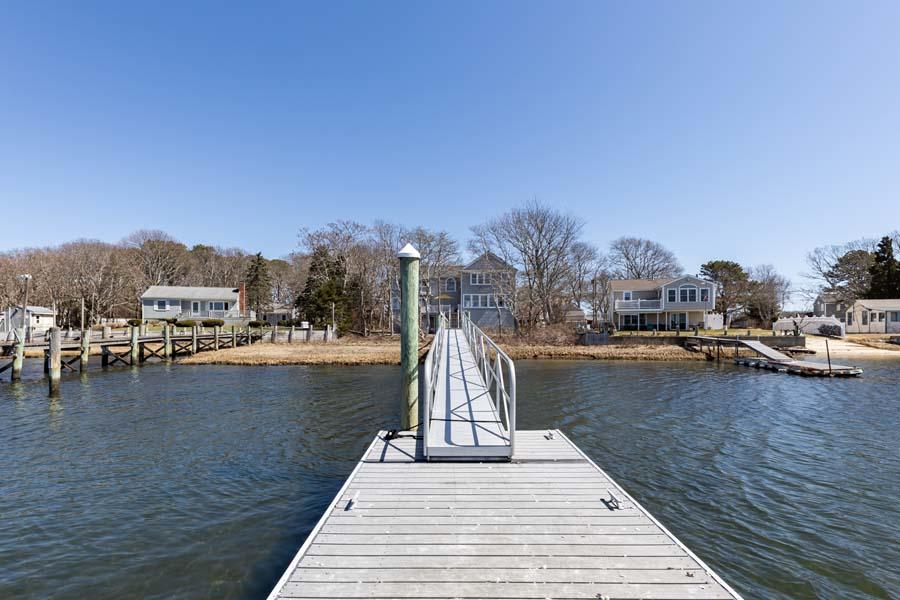 99 Monomoscoy Road West Mashpee, MA 02649 - Photo 36 of 43 a view of a lake with a bench and trees in the background