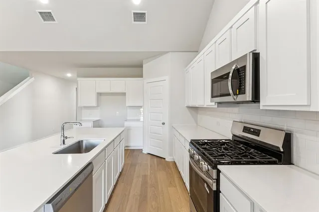 a kitchen with stainless steel appliances granite countertop a sink stove and microwave