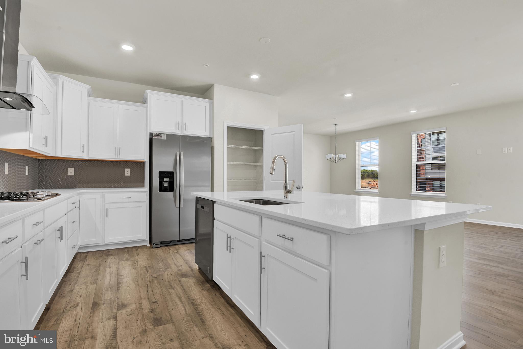 462 Herringbone Way Frederick, MD 21701 - Photo 8 of 29 a kitchen with granite countertop a refrigerator a sink dishwasher and white cabinets with wooden floor