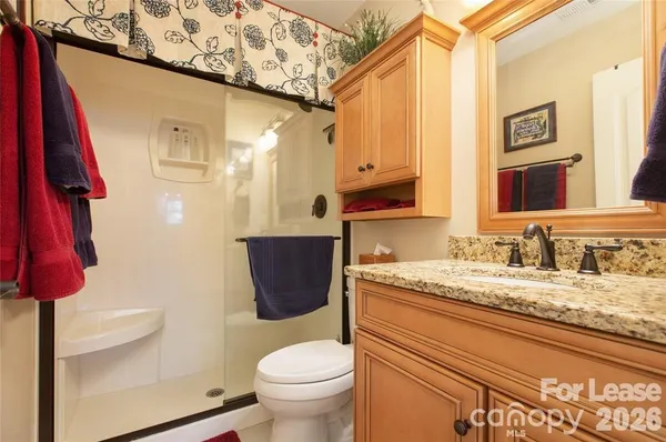 a bathroom with a granite countertop sink a toilet and a shower