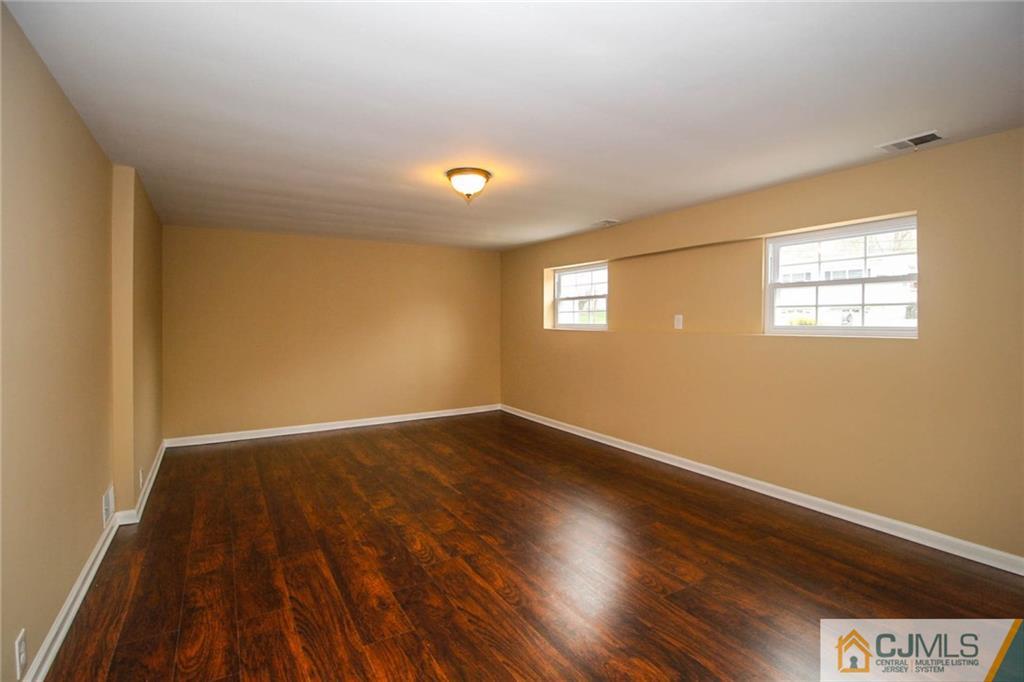 44 Harmon Road Edison, NJ 08837 - Photo 22 of 25 a view of an empty room with wooden floor and a window