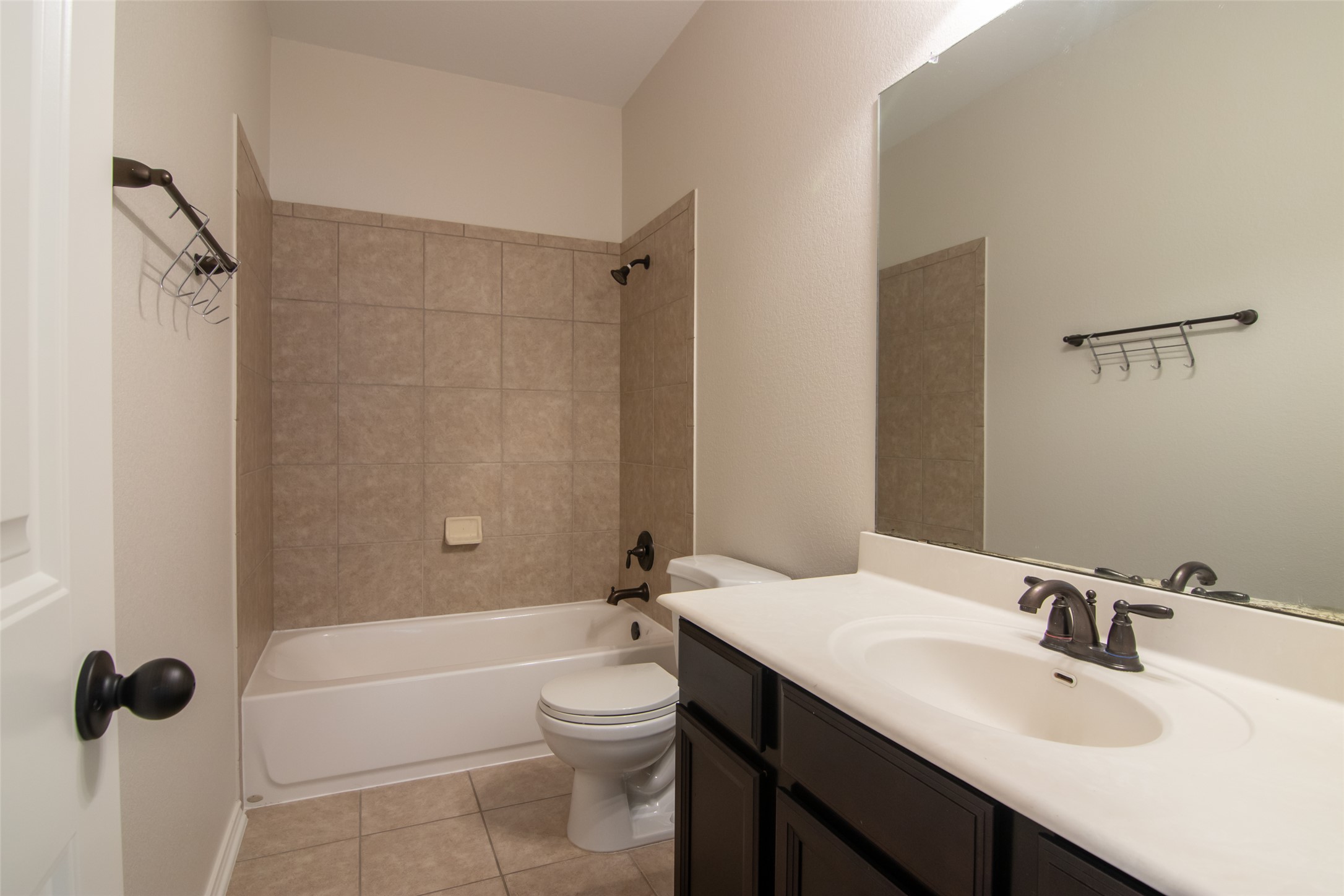 12104 Broten Street Austin, TX 78748 - Photo 27 of 32 Functional full bathroom featuring a tub-shower combination with tiled walls and a vanity with an integrated sink.
