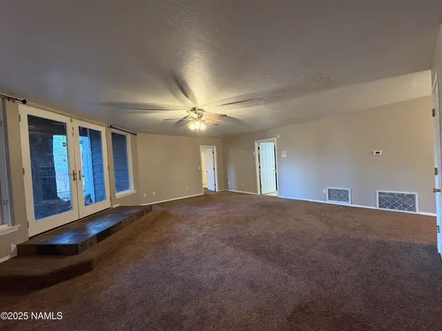 a view of an empty room with window and chandelier fan