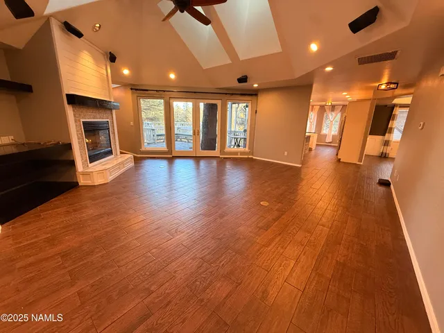 a view of empty room with wooden floor and fan