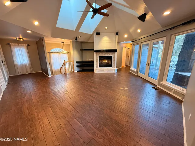 a view of an empty room with wooden floor a fireplace and a window