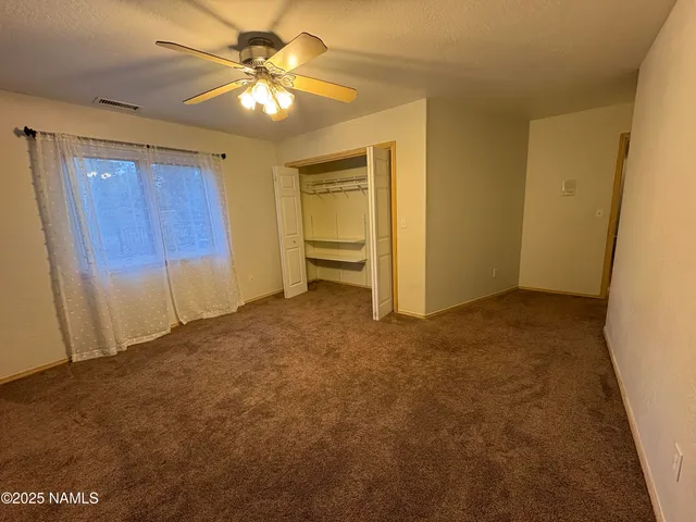 a view of an empty room and chandelier fan