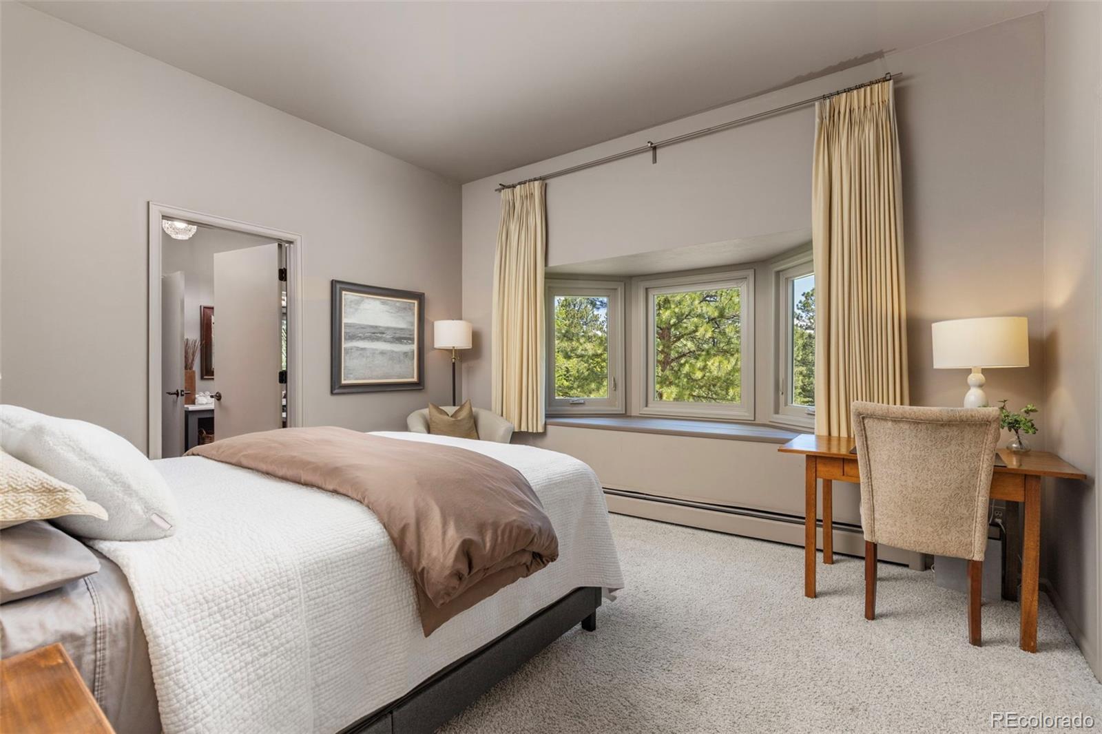 1323 South Snyder Gulch Road Evergreen, CO 80439 - Photo 36 of 47 a spacious bedroom with a bed and a table lamp on closet