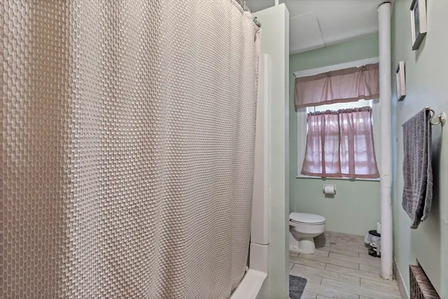 a bathroom with a toilet a window and shower