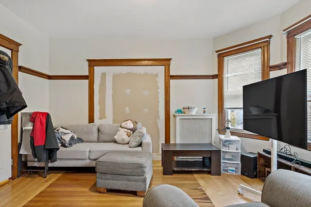 a living room with furniture a flat screen tv and a refrigerator