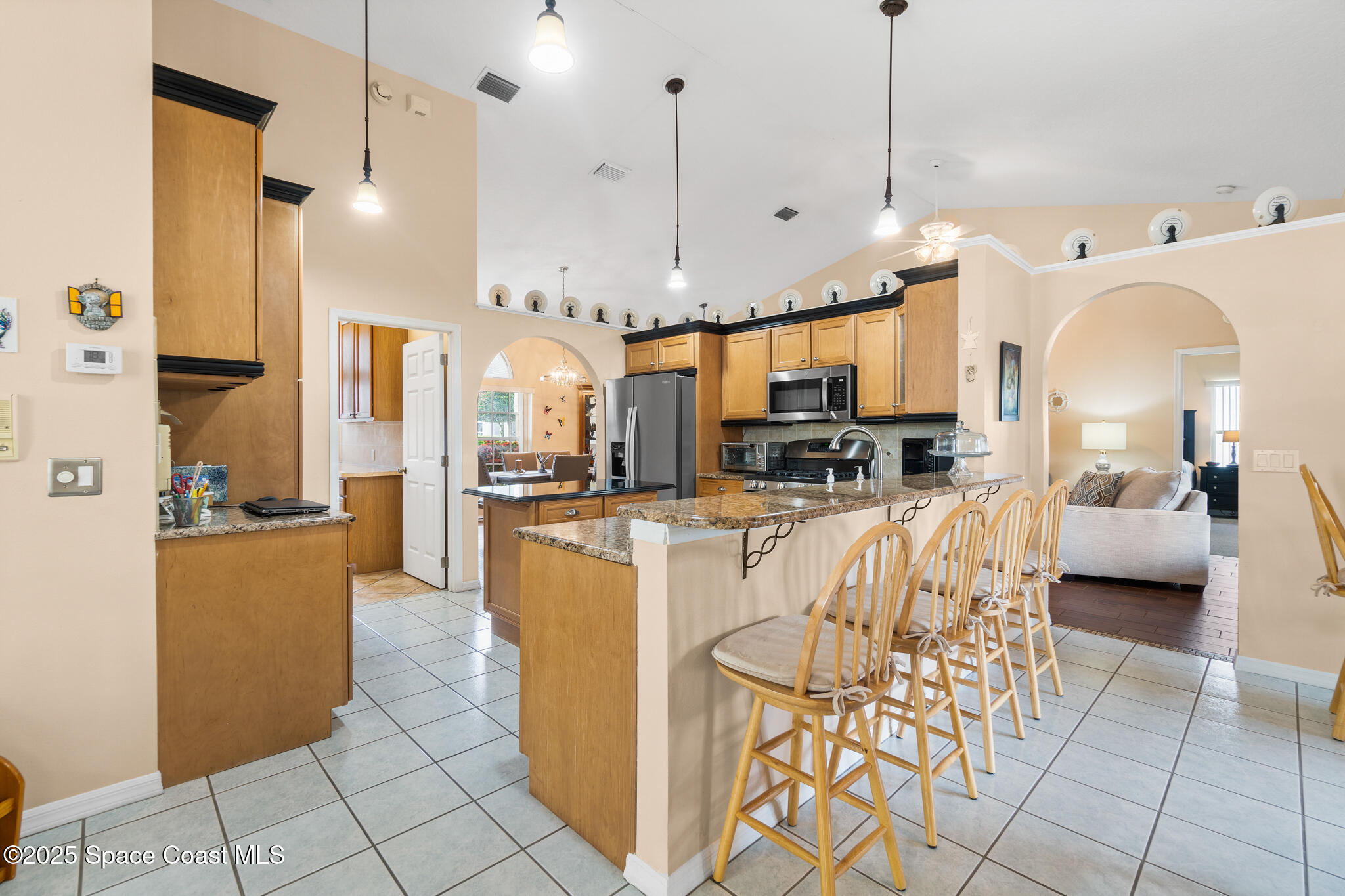 4808 Springwater Circle Melbourne, FL 32940 - Photo 10 of 38 a kitchen with stainless steel appliances kitchen island granite countertop a refrigerator a stove a sink a oven and a dining table with wooden floor