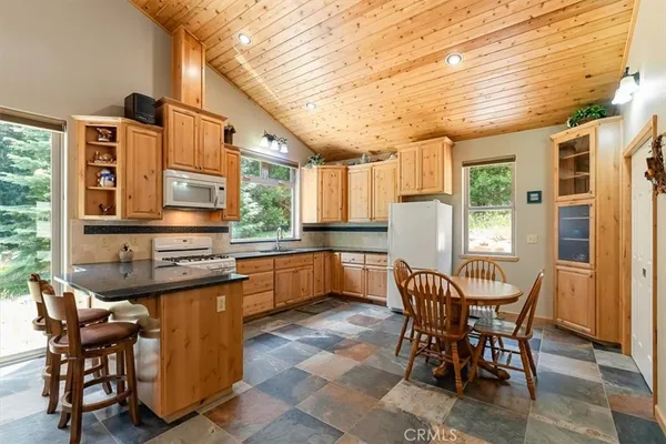 a kitchen with stainless steel appliances granite countertop table chairs and a refrigerator