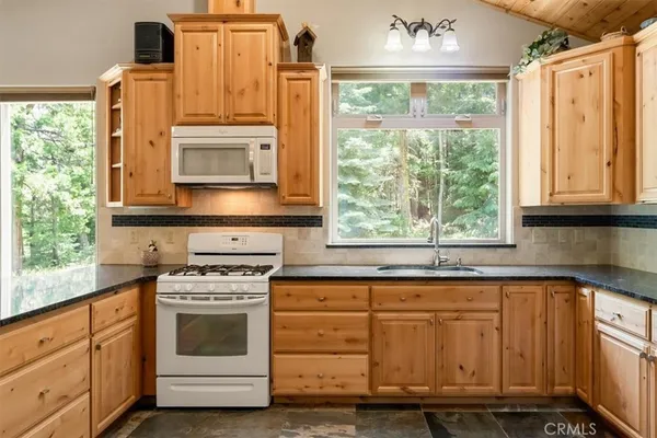 a kitchen with granite countertop a stove a sink and a microwave