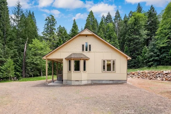 a view of a house with a yard and tree in the background