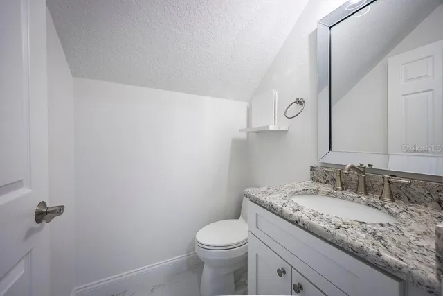 a bathroom with a granite countertop sink a toilet and a mirror