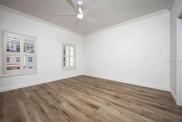 a view of empty room with wooden floor and fan